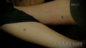 Фото тату на руке: две маленькие коричневые точки, расположенные рядом друг с другом. Минималистичный и необычный рисунок татуировки.