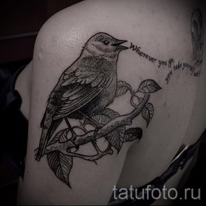 Фото тату птицы, сидящей на ветке, с надписью "Wherever you go, you take yourself with you". Черно-белый рисунок, графичный стиль, вдохновляющая цитата.