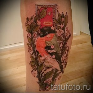 Фото тату птицы, окруженной цветами и листьями, в обрамлении прямоугольника. Мягкие цвета, детальная проработка, нежный и романтичный дизайн.
