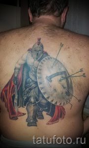 Фото тату на спине мужчины: спартанский воин с мечом и щитом, окруженный стрелами. Детализированный рисунок в стиле реализм.