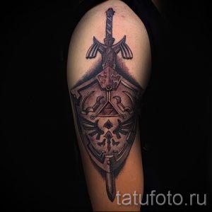 Фото детализированной тату на руке с изображением меча и щита из игры The Legend of Zelda. Черно-серый рисунок татуировки в стиле аниме и видеоигр.