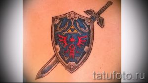 Фото тату на руке с изображением меча и щита из игры The Legend of Zelda. Черно-серый рисунок татуировки в стиле аниме и видеоигр.