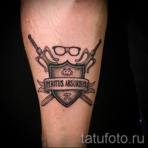 Фото татуировки на руке с изображением щита, очков и символа пи. Оригинальный рисунок татуировки в черно-белых тонах.