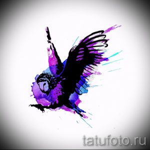 Фото тату с изображением летящей совы, выполненной в технике акварели с использованием фиолетовых, синих и черных оттенков.