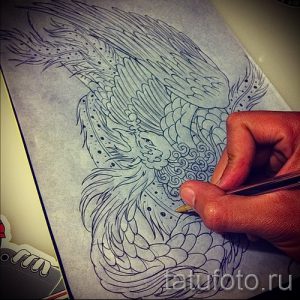 Карандашный эскиз татуировки феникса, изображающий процесс работы мастера тату. Детализированный рисунок с проработкой перьев и анатомии птицы.