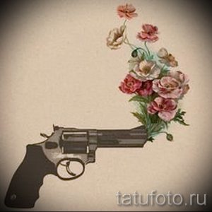 Фото татуировки с изображением пистолета, из ствола которого растут яркие полевые цветы. Необычный и символичный рисунок.