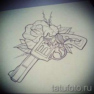 Черно-белый эскиз татуировки с изображением револьвера, обвитого бутоном розы. Детализированный рисунок для вдохновения.