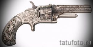 Детализированный эскиз татуировки с изображением старинного револьвера, украшенного сложной гравировкой. Рисунок выполнен в реалистичном стиле.
