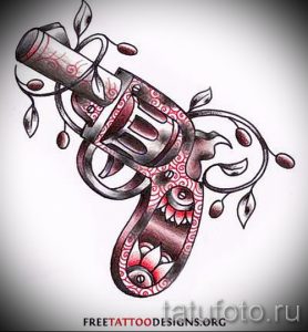 Фото тату с изображением пистолета, обвитого ветвями с листьями и ягодами. Рисунок выполнен в черно-красной гамме и имеет реалистичный вид.
