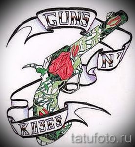 Фото тату с изображением пистолета, обвитого розовыми кустами, и надписью "Guns N' Roses". Эскиз выполнен в ярких цветах с использованием красного, зеленого и черного оттенков.