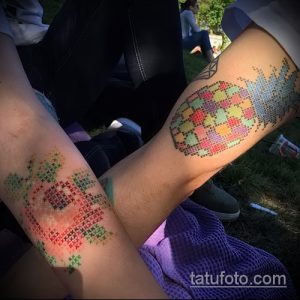 Фото парных татуировок ананаса, выполненных в стиле кросс-стич. Изображения расположены на бедрах двух людей.