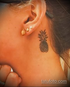 Фото маленькой татуировки ананаса за ухом. Детализированный рисунок в стиле blackwork, выполненный тонкими линиями. Идеально подходит для любителей минимализма.