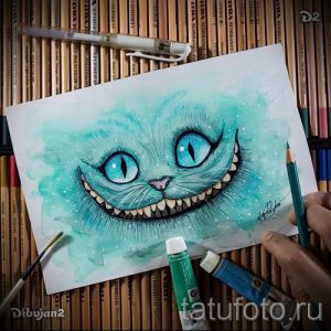 Фото тату: акварельный рисунок Чеширского кота с яркими голубыми глазами и бирюзовой шерстью, выполненный в технике акварели.