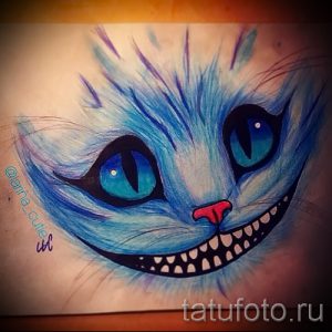 Фото тату эскиза Чеширского Кота с яркими голубыми глазами и оскаленной улыбкой. Рисунок выполнен в технике цветного карандаша.