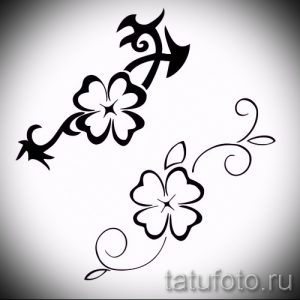 Черно-белый эскиз татуировки с изображением двух четырехлистных клеверов, соединенных изящными узорами и завитушками. Идеально для минималистичного дизайна.