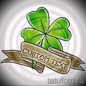 Фото тату четырехлистного клевера с лентой и надписью 'CUSTOM TEXT'. Яркий рисунок татуировки в стиле олдскул.
