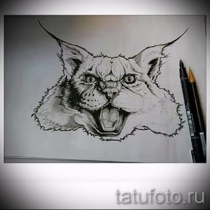 Черно-белое фото эскиза тату рыси с открытой пастью, демонстрирующей зубы. Рисунок выполнен в графичном стиле с акцентом на выразительность.