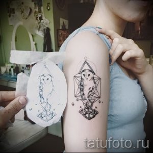 Фото татуировки совы в геометрическом стиле, выполненной на плече. Минималистичный рисунок тату с использованием черных линий и геометрических фигур.
