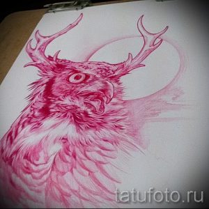 Яркий эскиз татуировки, изображающий голову мифического существа с телом птицы и оленьими рогами. Рисунок выполнен в красных тонах с детальной прорисовкой перьев и рогов.