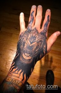 Фото тату демонического козла на руке. Черно-белая татуировка в стиле blackwork с использованием плотной штриховки.