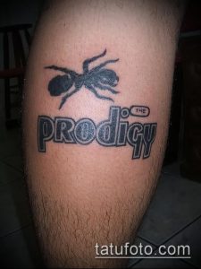 Фото тату с изображением муравья над логотипом группы The Prodigy. Черно-белый рисунок, выполненный в простом стиле. Расположение на икре.