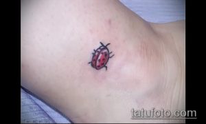Фото минималистичной татуировки божьей коровки на ключице. Небольшой, но выразительный рисунок татуировки в черных тонах.