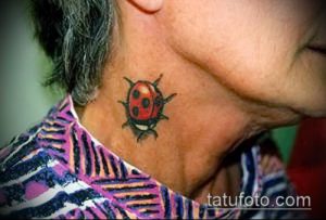 Фотография небольшой татуировки с изображением красной божьей коровки с черными точками на шее женщины. Рисунок выполнен в реалистичном стиле.