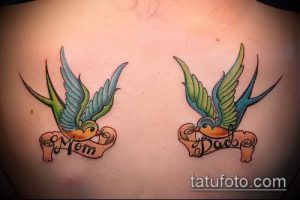 Фото пары татуировок ласточек с надписями 'Mom' и 'Dad' на спине, выполненных в стиле олдскул с яркими цветами.