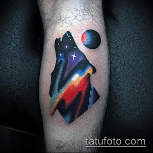 Фото татуировки волка, выполненной в ярких космических цветах. Изображение волка сливается с изображением галактики и планет.