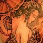 Фото тату на спине с изображением гейши, держащей веер, и черепа. Рисунок выполнен в черно-серых тонах с добавлением красных акцентов.