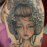 Фото тату гейши с цветами в волосах, выполненное в черно-серых тонах на плече, с акцентом на детализацию лица.