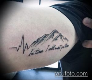 Черно-белое фото татуировки на руке с изображением гор, пульса и фразы 'In time, I will meet you there'. Минимализм, тонкие линии.