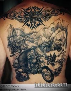 Масштабная татуировка на спине с изображением мотоциклиста на мотоцикле Harley Davidson, едущего по горной дороге. Логотип Harley Davidson и горный пейзаж.