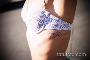 Фото тату: изящная татуировка с изображением горной цепи на боку, выполненная в тонких линиях. Женственный и минималистичный эскиз тату.