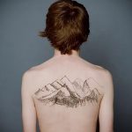 Фото тату гор на мужской спине. Черно-белый рисунок, минималистичный стиль, тонкие линии.