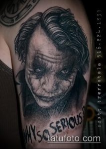 Фото тату реалистичного портрета Джокера в черно-белой гамме с надписью 'WHY SO SERIOUS?'. Рисунок выполнен на руке.
