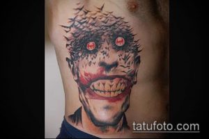 Фотография татуировки Джокера с шипами на голове и красными глазами, выполненной в ярком и агрессивном стиле.