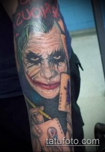 Фото тату Джокера на руке: реалистичный портрет, карты, карандаш, надпись "SERIOUS". Идеально для поклонников фильма "Темный рыцарь".