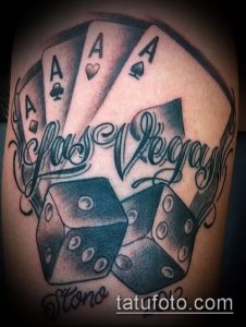 Фото татуировки на руке с надписью 'Las Vegas', игральными картами и костями. Выполнена в черно-серых тонах.