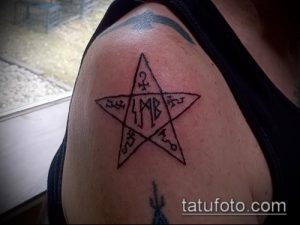 Черно-белое фото татуировки на плече с изображением пентаграммы, вписанной в пятиугольник, с руническими символами внутри.