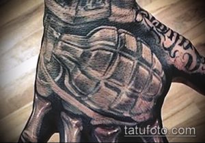 Фото тату гранаты на ладони, выполненной в технике black and grey с высокой детализацией и реалистичными тенями.