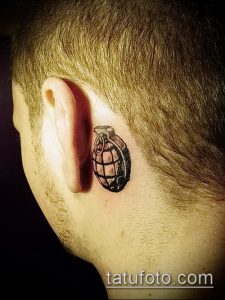 Фото тату гранаты, выполненной в технике blackwork, расположенной за ухом. Лаконичный и стильный рисунок.