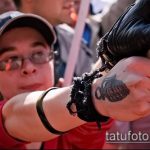 Фото тату гранаты на руке человека, участвующего в протесте. Рисунок татуировки в черно-серых тонах.