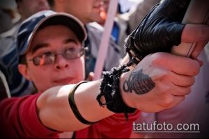 Фото тату гранаты на руке человека, участвующего в протесте. Рисунок татуировки в черно-серых тонах.
