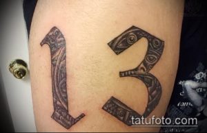 Фото тату цифры 13, выполненной в черно-серых тонах с использованием геометрического орнамента на бедре.