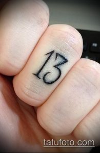 Фото тату на пальце: маленькая цифра 13, минималистичный стиль, черно-белый рисунок.
