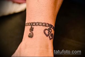 Фото тату: браслет на запястье с буквами 'S' и 'R', выполненный в стиле тонкой графики. Изящный рисунок татуировки для девушек.