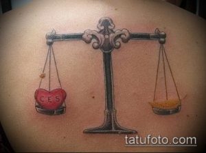 Фото татуировки на спине с изображением весов, где на одной чаше находится сердце. Символизирует баланс между любовью и справедливостью.