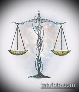 Фото татуировки с изображением весов правосудия на фоне акварельного неба. Детализированный рисунок, выполненный в мягких тонах.