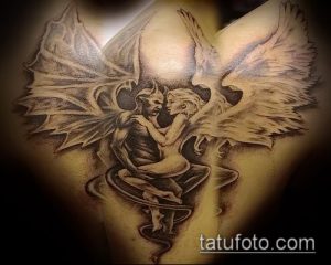 Фото тату на руке с изображением ангела и демона, обнимающих друг друга. Черно-белый рисунок с детально проработанными крыльями и лицами.